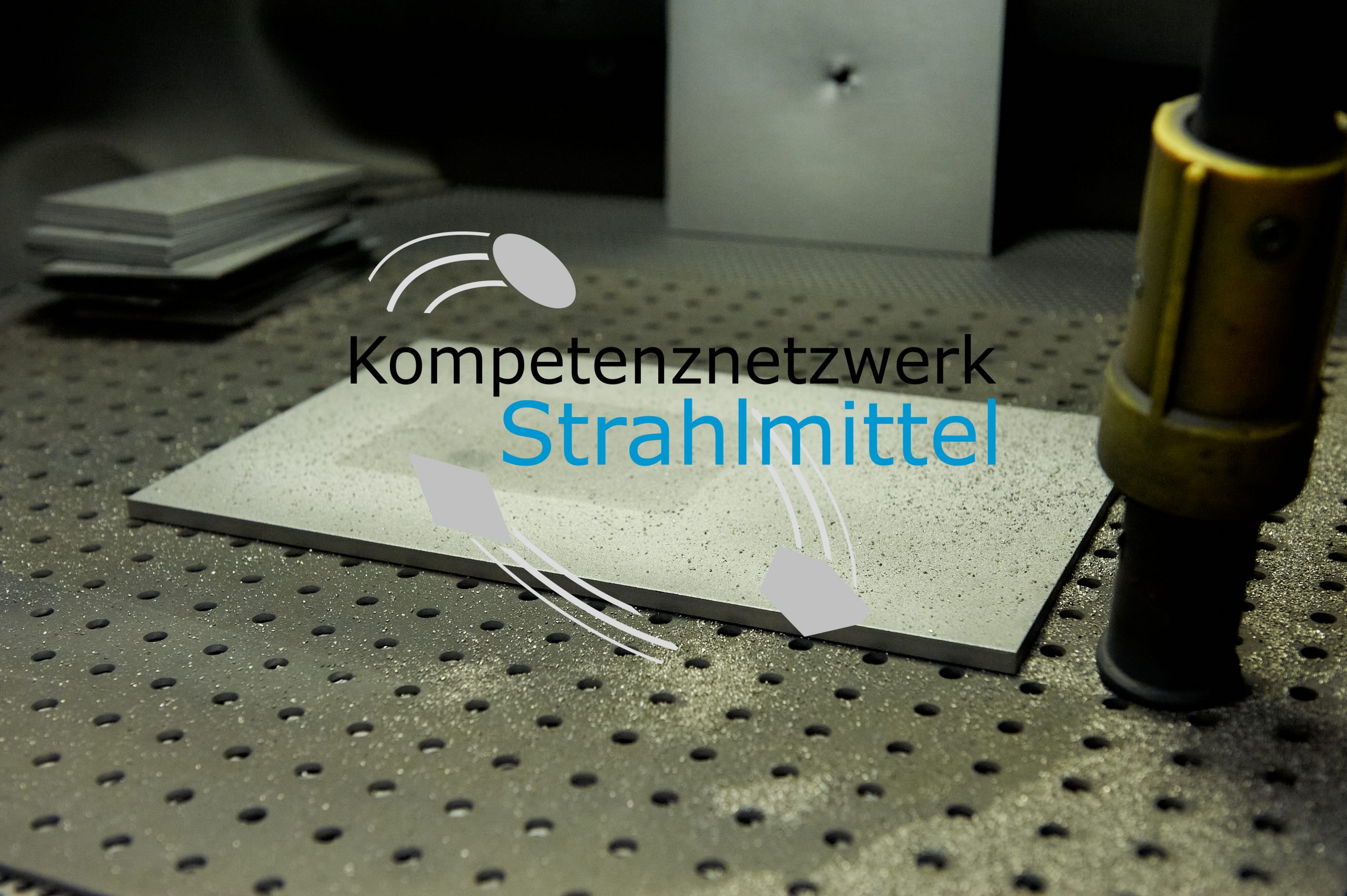 Einblick in eine Handstrahlkabine des IKS Dresden; im Vordergrund: Logo des Kompetenznetzwerk Strahlmittel